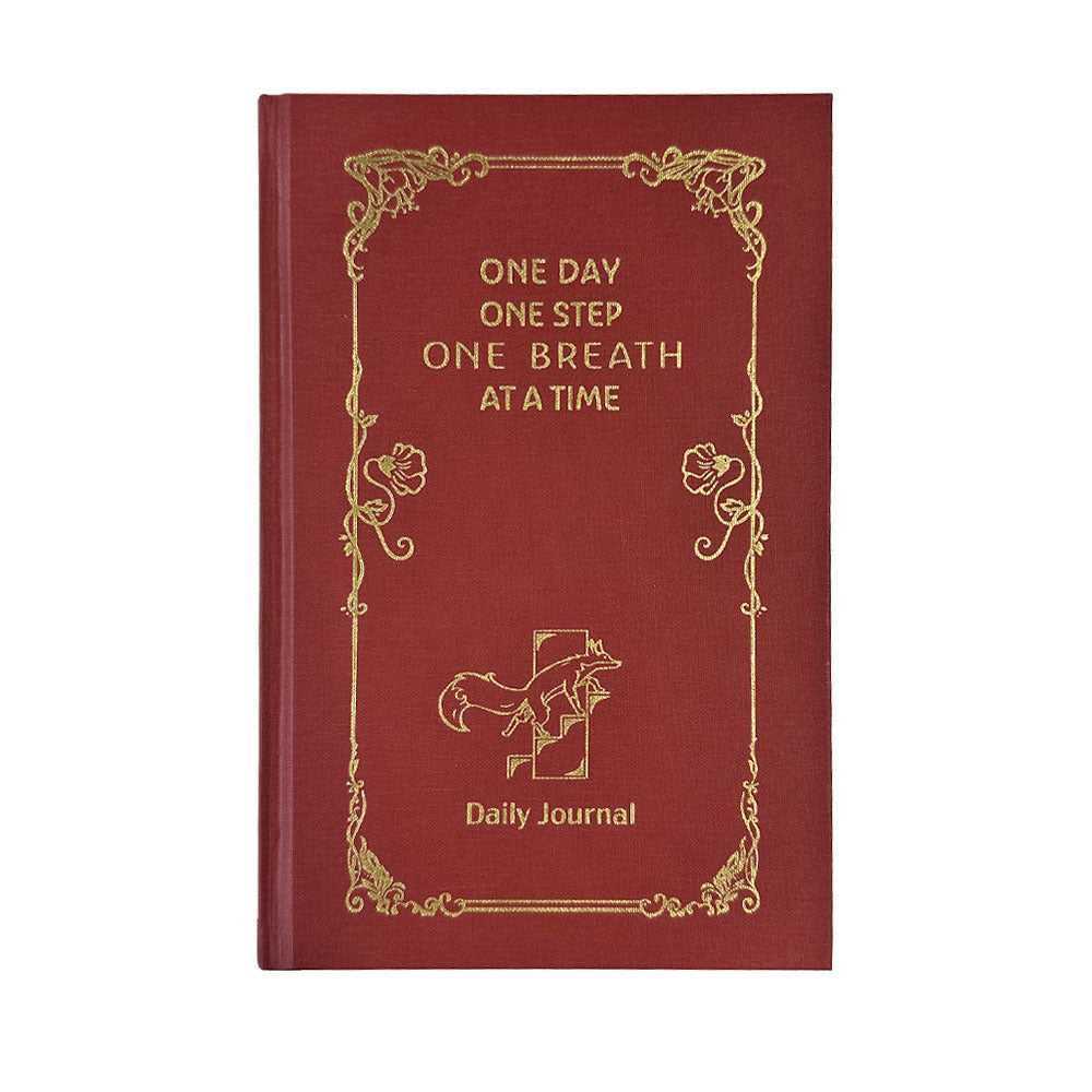 Strength Daily Journal in red, a hardcover 90-day guided self-care journal with gold-foil cover and ribbon bookmark.